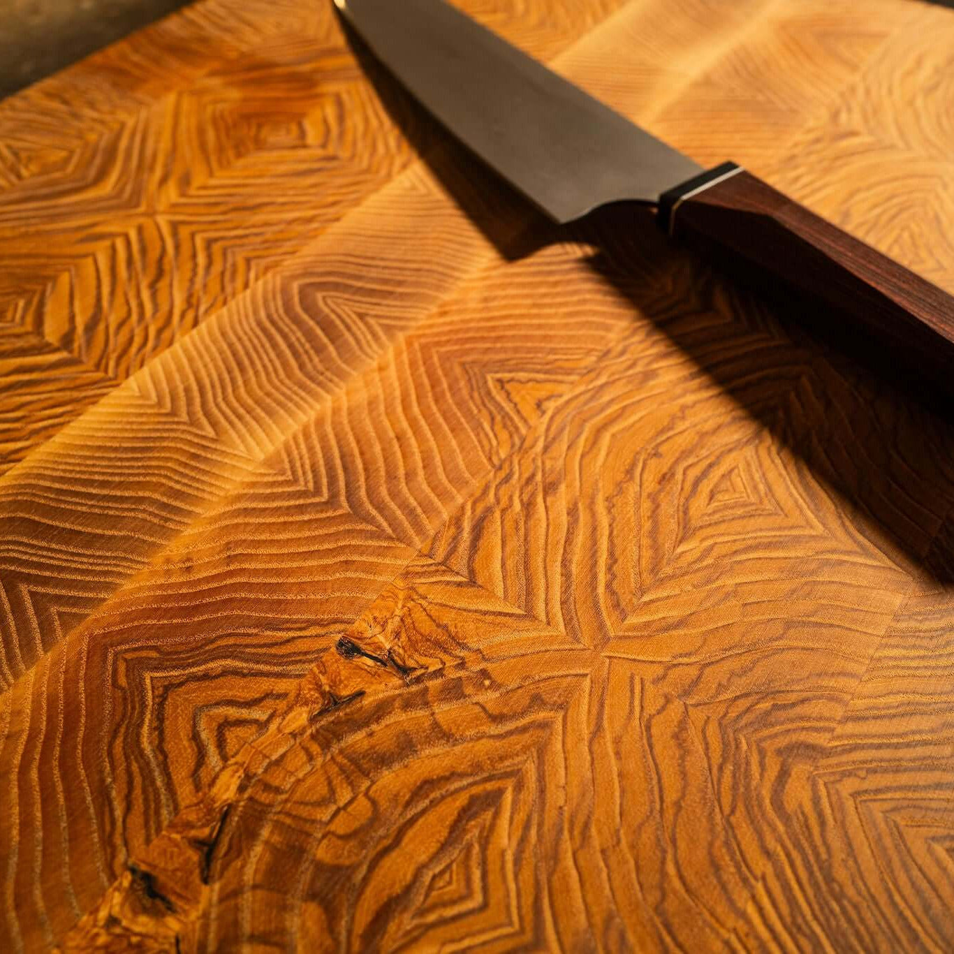 Olivenesche Stirnholzschneidebrett mit einzigartiger Maserung und Küchenmesser auf der Oberfläche.