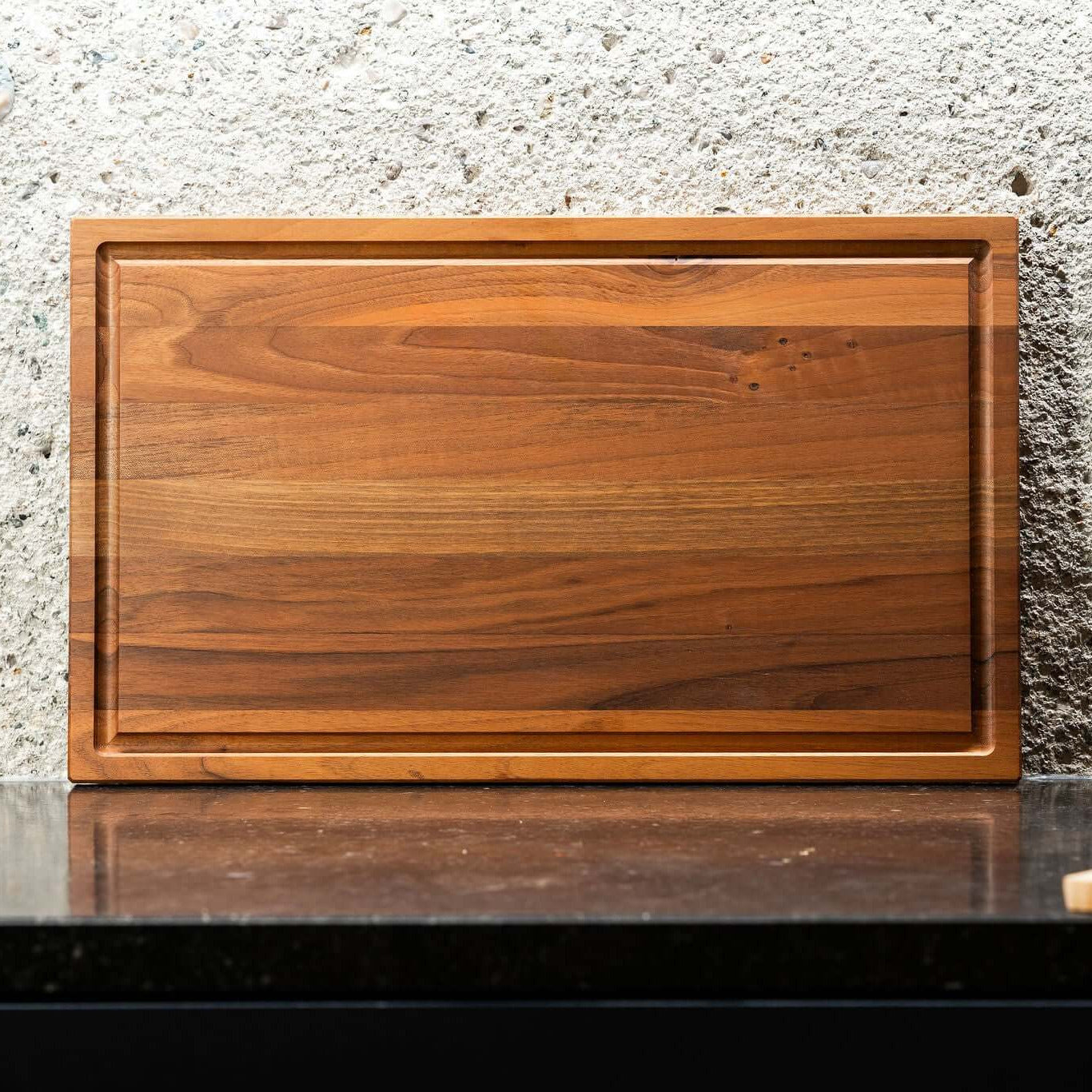 Nussbaum Längsholzschneidebrett auf einer schwarzen Oberfläche, elegant und funktional.
