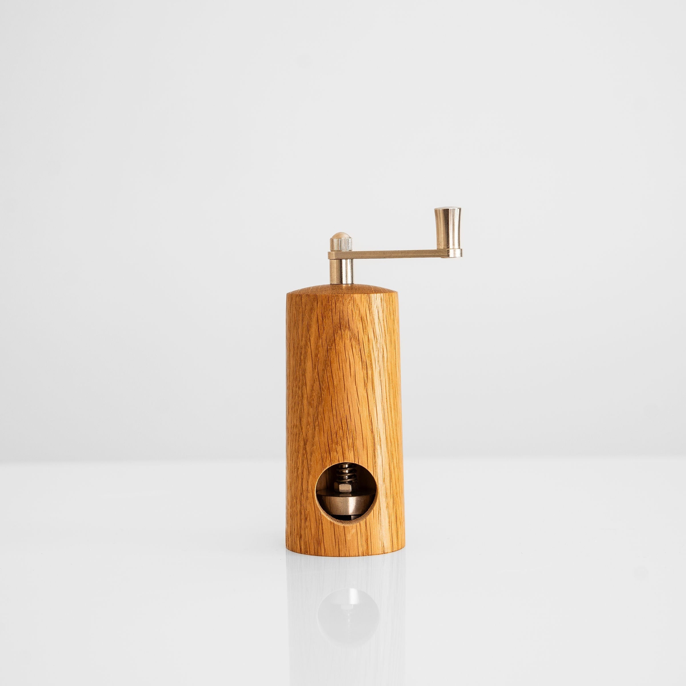 handgefertigte Muskatnussmühle aus Eiche und Nussbaum auf weißem Hintergrund, elegantes Design und funktionales Mahlwerk.