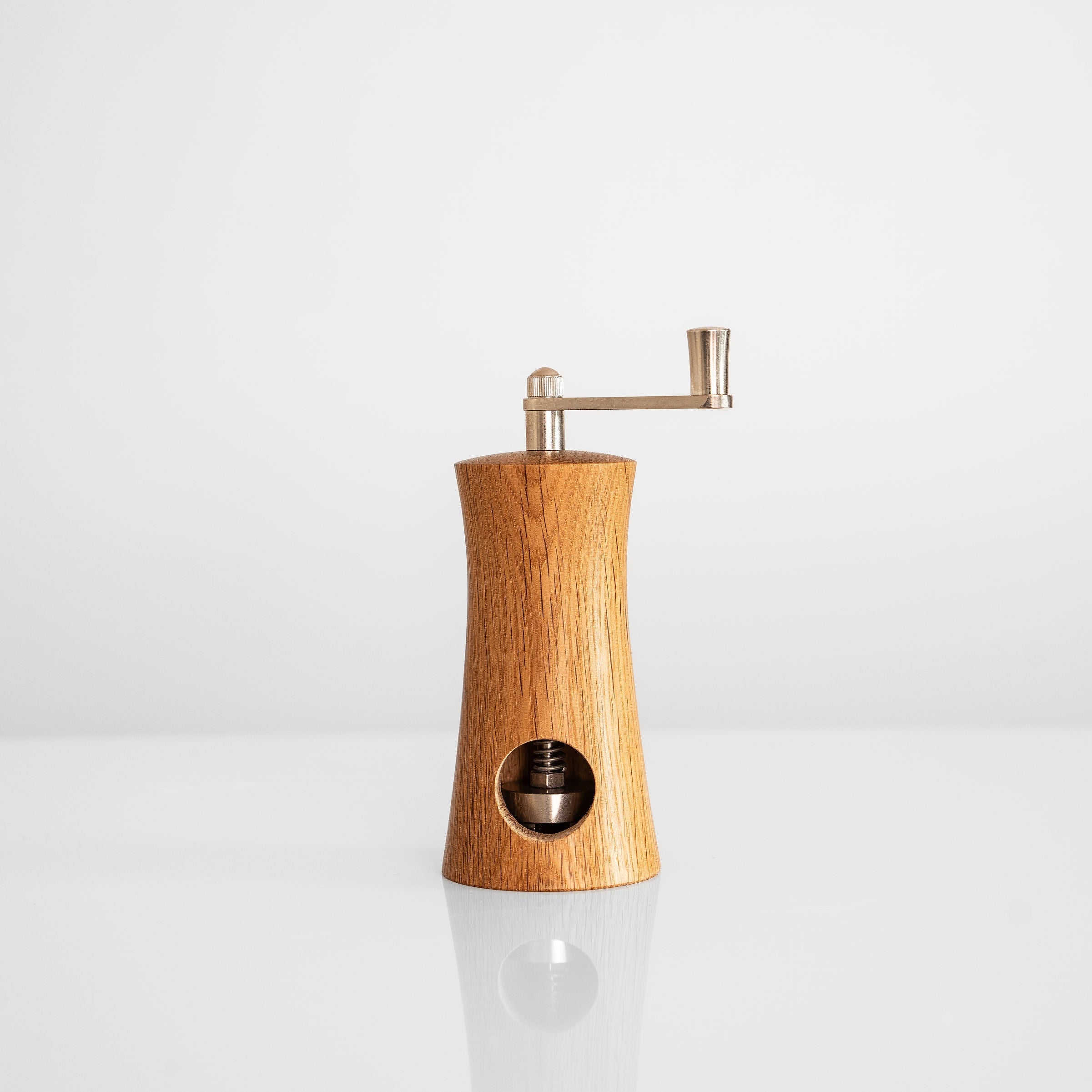 handgefertigte Muskatnussmühle aus Eiche und Nussbaum in elegantem Design auf weißem Hintergrund.